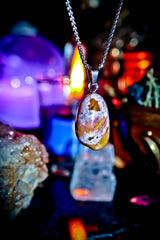 Necklace with a pendant featuring a natural stone design, set against a mystical background with candles and crystals.