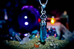 Blue crystal pendant on a dark background with mystical elements