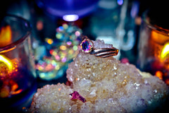 Gold ring with a colorful gemstone on a crystal rock with blurred lights in the background