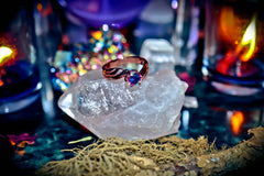 Ring with a colorful gemstone on a crystal with candles and crystals in the background