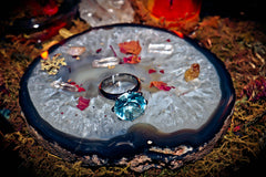 Jewelry on a decorative stone surface with candles and crystals in the background