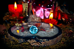 Witches' altar with a blue crystal, candles, and various items on a dark background