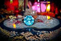 Blue gemstone ring on a mystical altar with candles and crystals