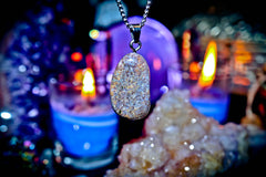 Necklace with a glittery pendant on a dark background with candles