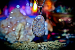 Necklace with a textured pendant against a blurred natural background