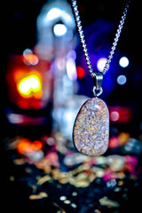 Sparkling pendant necklace against a blurred colorful background