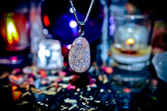 Sparkling pendant necklace on a dark background with candles and decorative elements