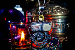 Witchcraft Silver pendant with a yellow gemstone on a dark background