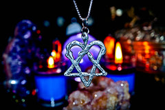 Silver heart and star of David pendant on a blurred candlelit background