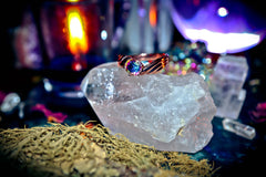Ring with a colorful gemstone on a crystal with blurred mystical background