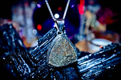 King Djinn Maymun Witchcraft Triangular pendant necklace on a textured surface with a blurred background