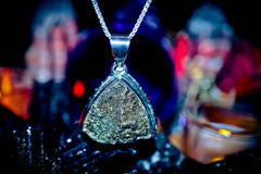 King Djinn Maymun Close-up of a silver pendant with a textured design against a blurred background