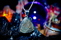 Djinn Amulet Diamond pendant necklace on a dark background with colorful blurred lights