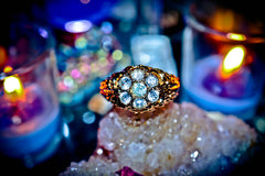 Gold ring with gemstones on a rock with candles in the background
