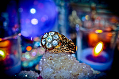 Gold ring with gemstones on a crystal with blurred candles in the background