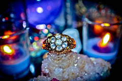 Gold ring with gemstones on a crystal with candles in the background